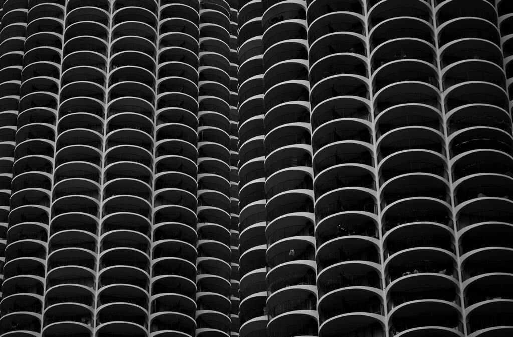 Low angle view of a modern skyscraper with curved balcony pattern in black and white.